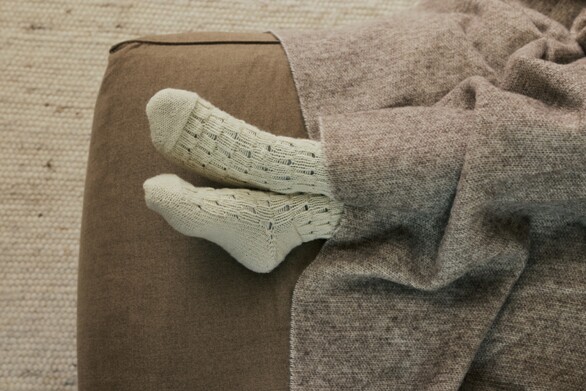 Schwangere liegt auf dem Sofa mit Wollsocken an den Füßen